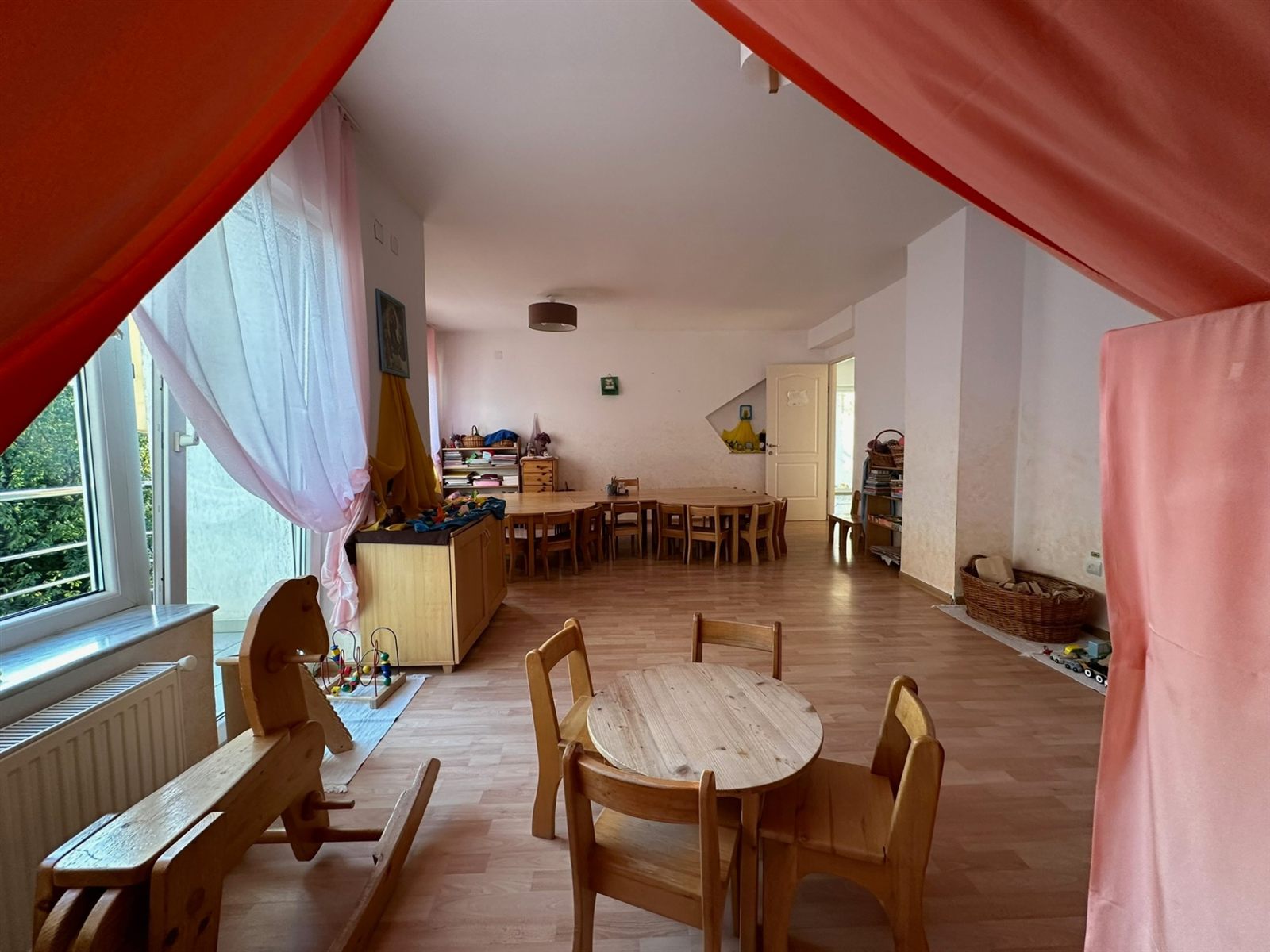 Sală de grupă luminoasă, cu mobilier din lemn natur